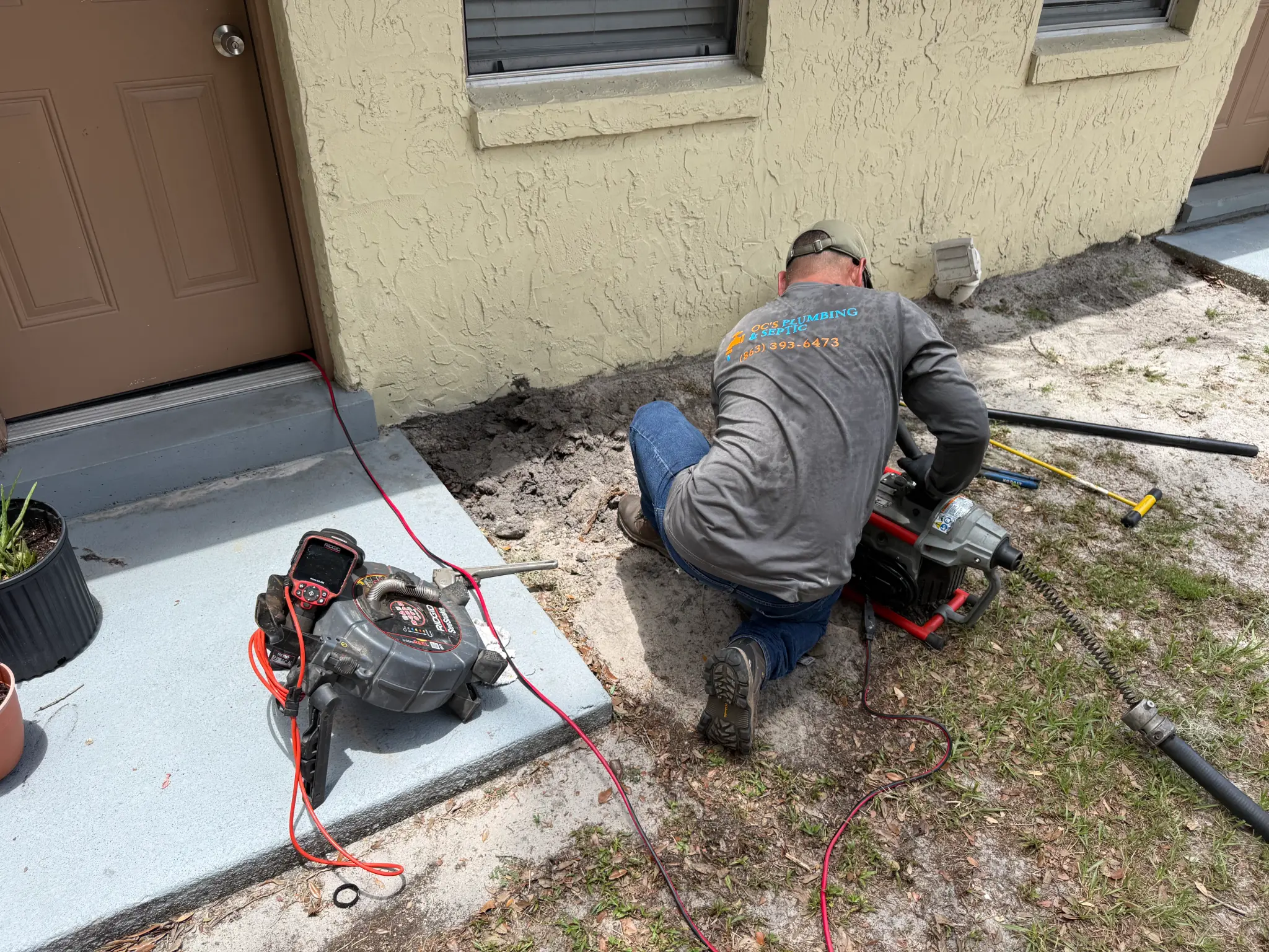 OC's Plumbing & Septic technician clearing a main line stoppage with professional drain equipment at a Central Florida home