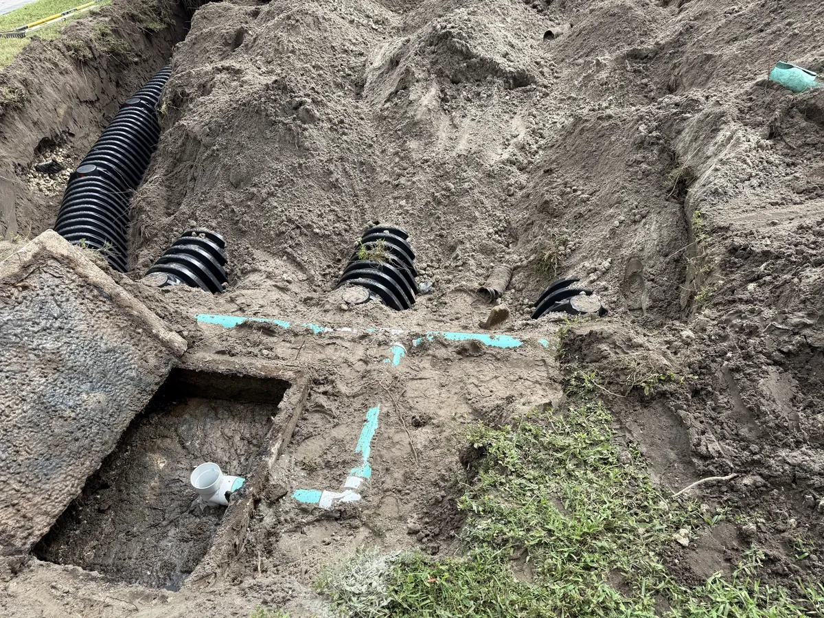 OC's Plumbing & Septic drain field installation showing infiltrator chambers and PVC piping in excavated trenches
