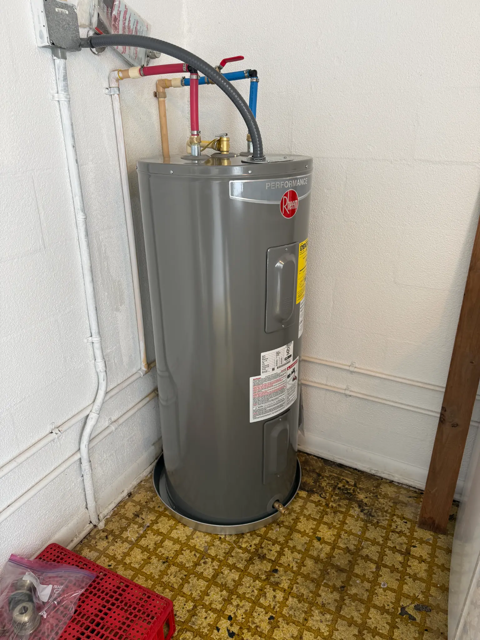 New Rheem water heater installed by OC's Plumbing & Septic with color-coded supply lines at a Lakeland home